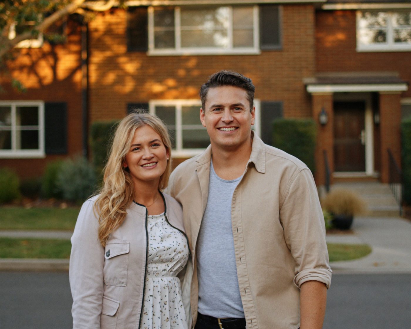 A couple standing proudly in front of their home